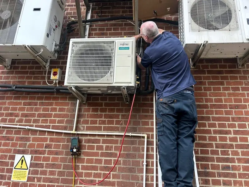 North engineer servicing an R32 outdoor unit with a digital gauge manifold